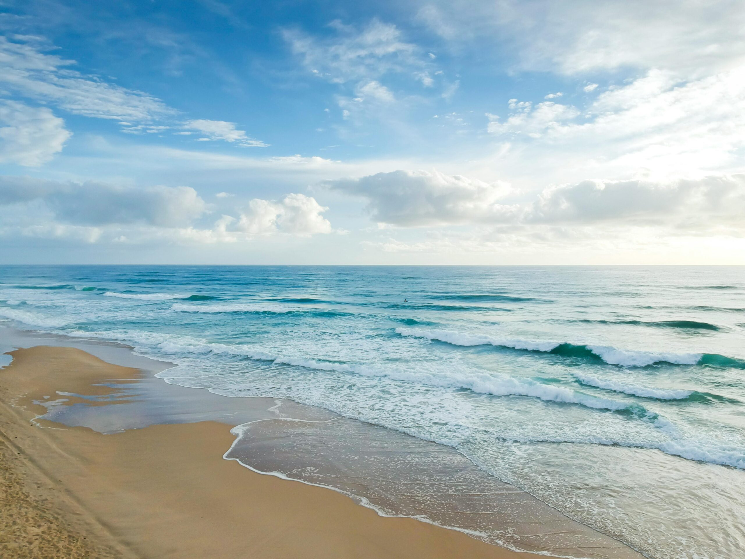 Serene view of gentle waves and sandy shore at Castaways Beach, QLD, Australia.