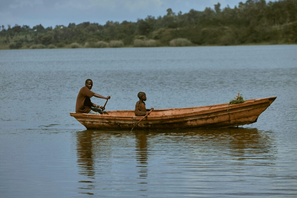 Two people in a wooden boat on a serene lake, reflecting nature.